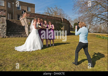 Horizontal portrait of a bride and bridesmaids at a wedding being photographed outside in the sun. Stock Photo