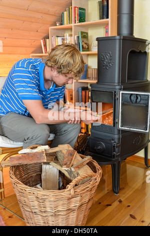 Young man making a fire in a stove Stock Photo