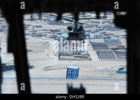 The view of a 10th Combat Aviation Brigade CH-47 Chinook helicopter sling loading a shipping container is seen from the cockpit Stock Photo