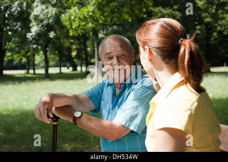 A women and an elderly man having a chat in a park Stock Photo