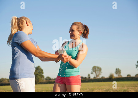 Two young women having fun with a bottle of water during a drink break while doing sports Stock Photo