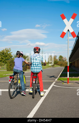 Children waiting with their bicycles in front of a railroad crossing at a traffic awareness course Stock Photo
