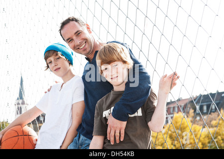 Two cool boys standing with their father on a playground Stock Photo