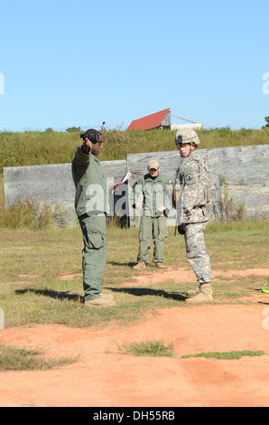 Enrico Warren of Fayetteville, N. C. left, gives instructions to selectee Sgt. Zachery M. Pryor of Litchfield, Ill. right, while Spc. Kevin Rogers of Red Hook, N. Y. center, serves as range safety for the threat - non-threat live-fire pistol range during Stock Photo