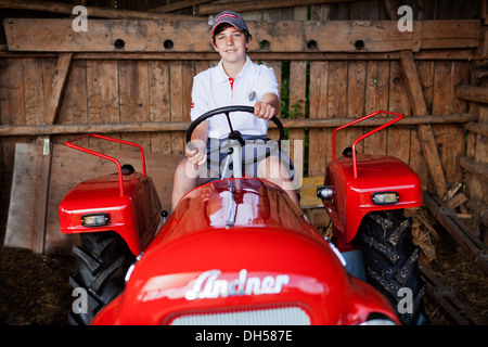 Boy sitting on a vintage tractor, Reith im Alpbachtal, Kufstein District, North Tirol, Tirol, Austria Stock Photo