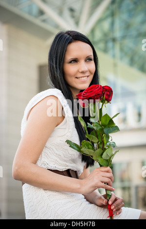 Young beautiful woman with red roses - outdoorf lifestyle portrait Stock Photo