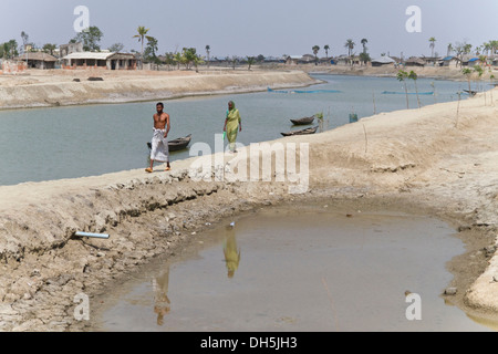 Man and a woman walking along a dam, Cyclone Aila severely flooded the town of Gabura in 2009, Sundabarns, Khulna District Stock Photo