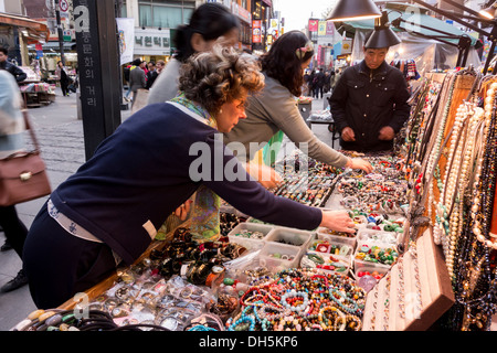 European woman and Korean women trying and choosing accessories from a street stall in Insadong, Seoul Stock Photo