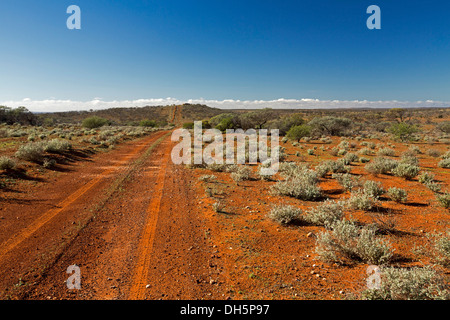 Australian outback landscape with long red road across vast treeless plains of sheep station in northern South Australia to distant horizon Stock Photo