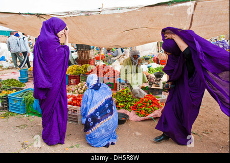 Three Berber women in front of a greengrocer's stall in the souks or bazaar area, Draa Vally, southern Morocco, Morocco, Africa Stock Photo