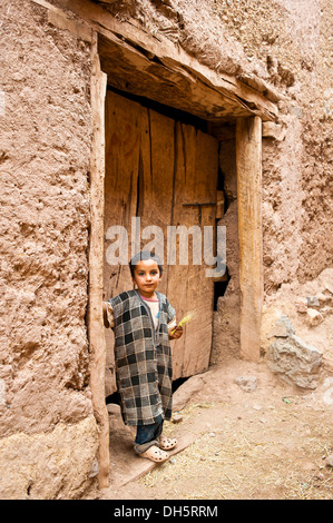 Little boy in a traditional Djellabah standing at a wooden gate, High Atlas mountain range, Morocco, Africa Stock Photo