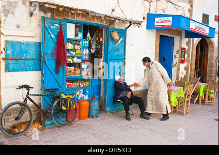Two men greeting each other in front of a small shop, Essaouira, Morocco, Africa Stock Photo