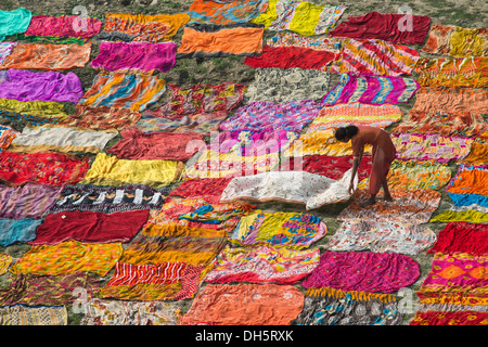 Colourful saris spread out to dry, a young woman spreading another sari on the ground, Flussufer am Yamuna, Agra, Uttar Pradesh Stock Photo