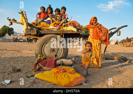 Four children sitting on a camel cart, woman and a little boy standing next to it, Pushkar Camel Fair, Pushkar, Rajasthan, India Stock Photo