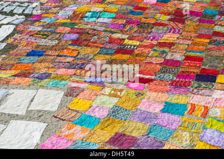 Colourful saris are laid out on the sand for drying after washing, Agra, Uttar Pradesh, India Stock Photo