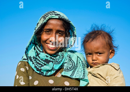 Indian woman with headscarf holding a little boy in her arms, portrait, Pushkar, Rajasthan, India Stock Photo