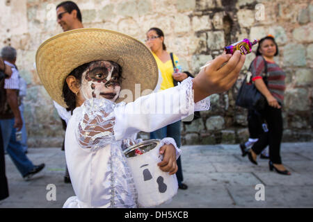 A child in costume hands out sweets during a parade celebrating the Day of the Dead festival known in spanish as D’a de Muertos in the historic center October 31, 2013 in Oaxaca, Mexico. Stock Photo