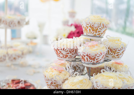 Fancy wrapped fairy cakes on cake stand with decorated tablecloth Stock Photo