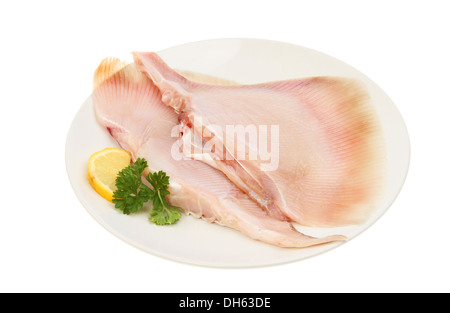 Two raw skate wings on a plate with lemon and parsley isolated against white Stock Photo