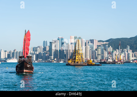 A traditional junk ship sails along Victoria Harbor in Hong Kong. Stock Photo