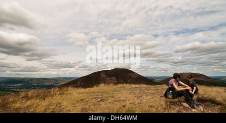 mother and son resting on the summit of Western Eildon with the other two summits in the background, Melrose Stock Photo