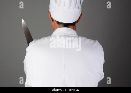 Closeup of a chef holding a knife. Man is seen from behind and is unrecognizable. Stock Photo