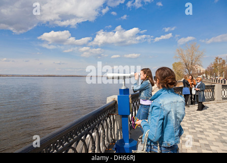 Girl looks through the coin operated binocular Stock Photo