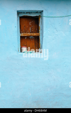 Boarded up window on the blue wall, Mana village, India Stock Photo