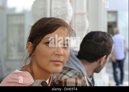 A young couple sitting side by side, looking in different directions, Konstanz or Constance, Baden-Wuerttemberg, PublicGround Stock Photo