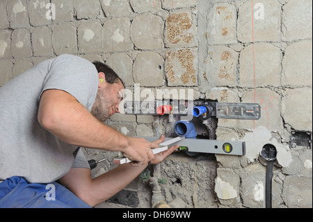 An electrician, systems mechanic for sanitary engineering, heating and air conditioning, installing a sewer pipe, refurbishment Stock Photo
