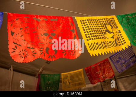 New York, NY, 31 October 2013.. Traditional paper cutout banners, called papel picado, hang from the tent. The red banner depicts a catrina, the skeletal head of a woman wearing an elaborate European-style hat. Credit:  Ed Lefkowicz/17�Թ����� Live News Stock Photo