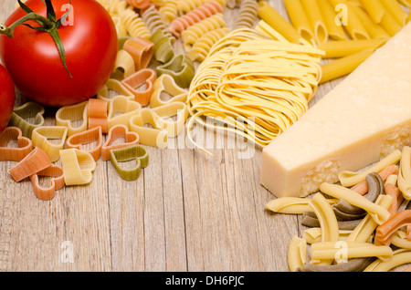 Different italian pasta, pecorino and red tomato on wood Stock Photo