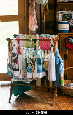 Hand crocheted blankets and kitchen towels displayed on a wooden drying rack in gift shop. Newberry, Florida USA Stock Photo