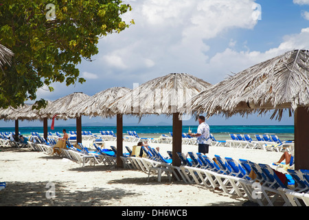 Thatch umbrellas, beach chairs and tourists, Palomino Island, El Conquistador Resort, Fajardo, Puerto Rico Stock Photo