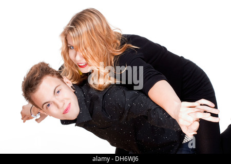 happy teenage couple piggybacking, arms outstretched, smiling. Stock Photo