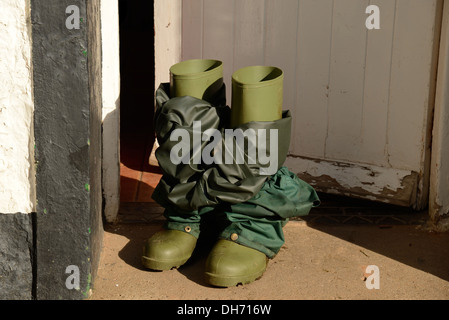 Rubber boots with waterproof pants at door. Stock Photo