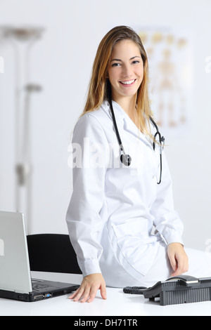 Beautiful female doctor sitting on the desk of her consultation Stock Photo