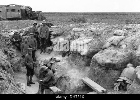 German troops rest in a frontline trench. In the background is a disabled British tank. Stock Photo