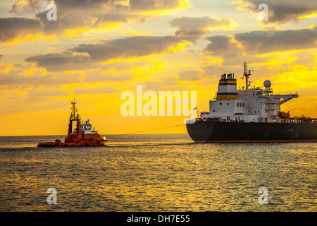 Tug boat pulling the tanker ship at sea. Stock Photo