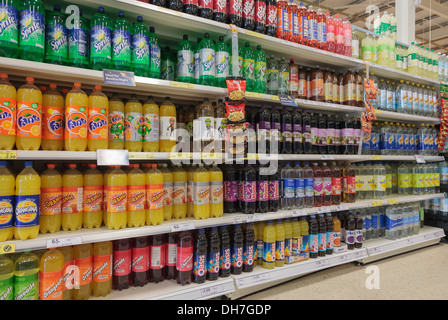 A variety of bottles of fizzy soft drinks sugary for sale on a Tesco supermarket aisle shelves. UK, Britain
