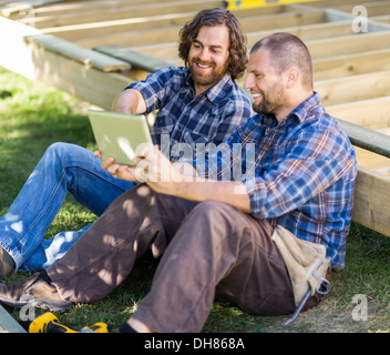 Happy Carpenters Using Digital Tablet At Construction Site Stock Photo