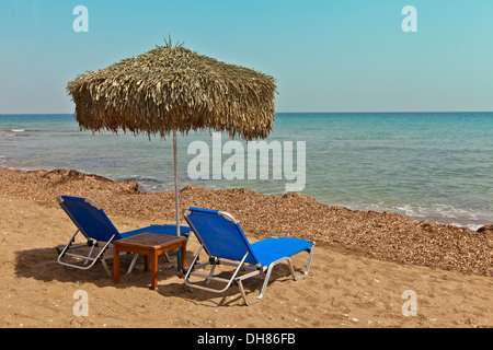 Beach scene with two sun loungers and sunshade. Stock Photo