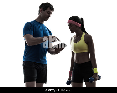 one woman exercising fitness workout with man coach using digital tablet in silhouette on white background Stock Photo