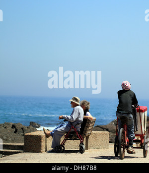 Elderly couple enjoying the view from Bloubergstrand while a ice cream seller cycles past. Stock Photo