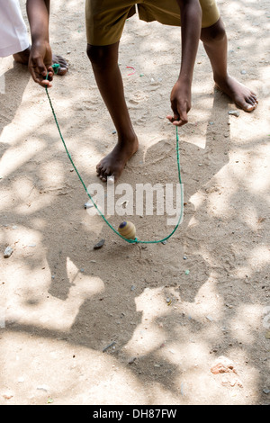 Rural Indian village boy playing with wooden spinning top toy. Andhra Pradesh, India Stock Photo