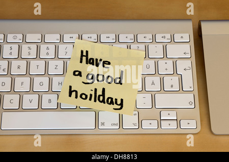 'Have a good holiday' sticky note on computer keyboard Stock Photo