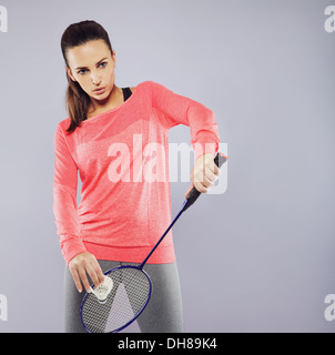 Portrait of attractive young woman with badminton racket ready to serve. Female badminton player playing against grey background Stock Photo