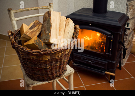 Basket full of logs in front of burning fire Stock Photo