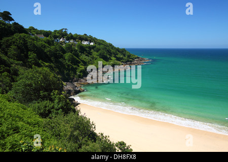 A golden sandy beach with turquoise blue sea and lush green cliffs. Stock Photo