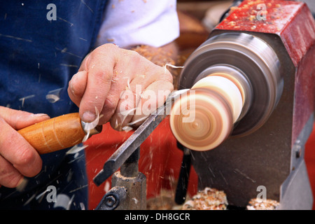 Woodworker handling gouge while working on wood with turning lathe in workshop of furniture maker Stock Photo